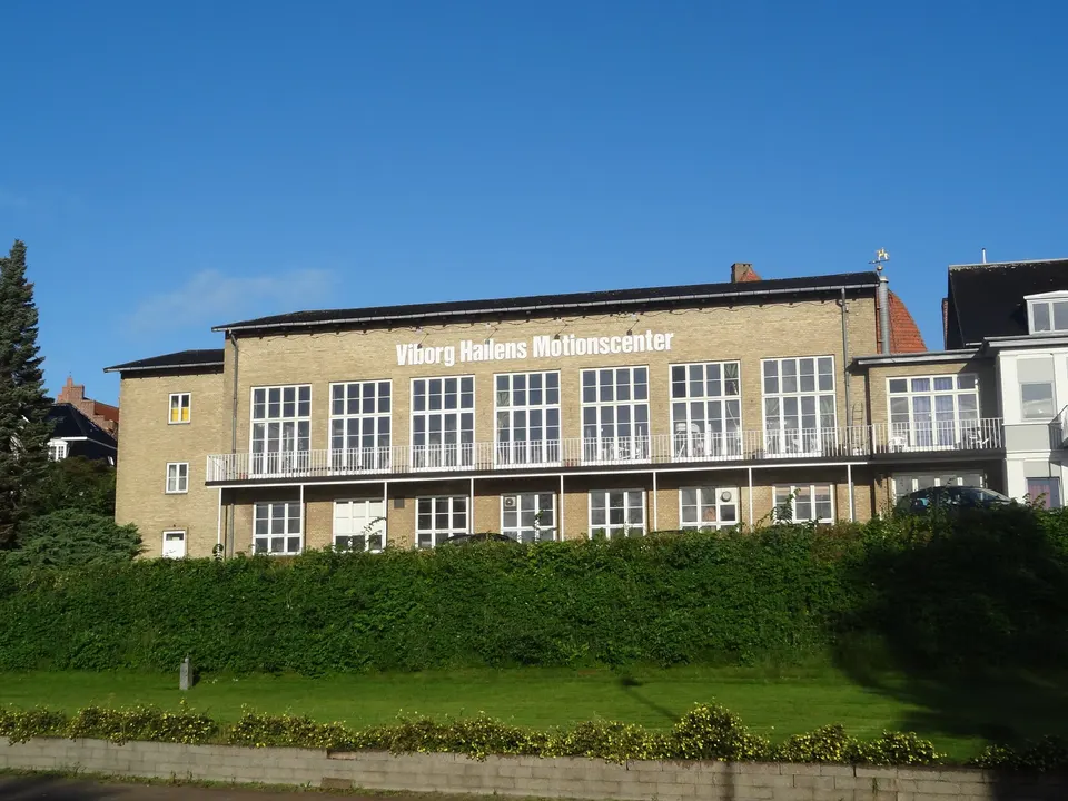 Viborg Hallen set fra vejen: gul murstensbygning med skiltet Viborg Hallens Motionscenter over en grøn skråning